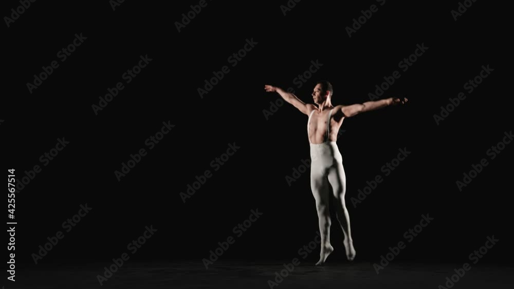 Male ballet dancer performs acrobatic element on a black background. Slow motion Male ballet dancer performs acrobatic element on a black background. Slow motion
