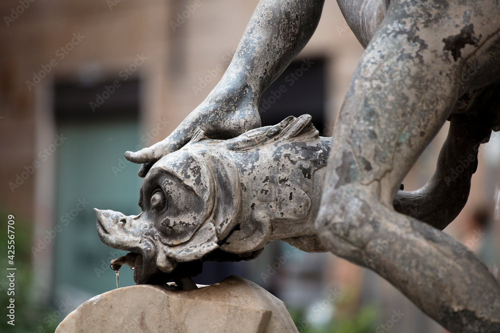 Detail of the Fountain of the Turtles in Piazza Mattei in central Rome, showing an ephebe resting their foot on a dolphin.