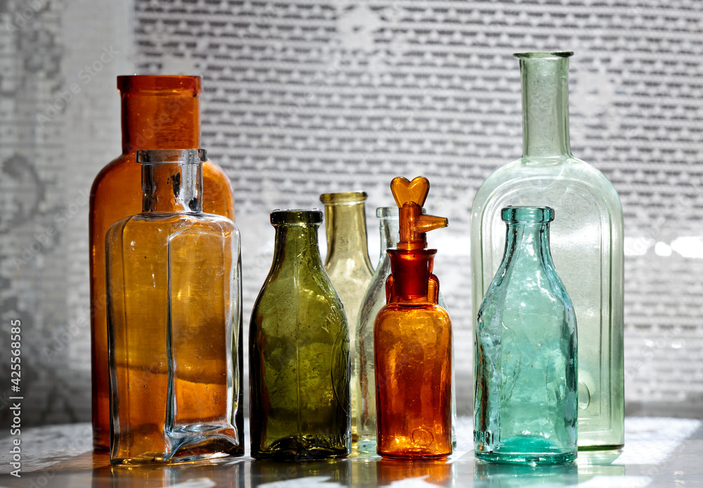 Antique glass bottles on a table next to a window