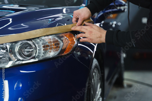 Man prepares car headlights for polishing..