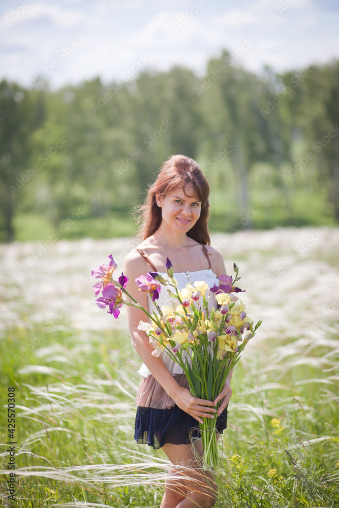 beautiful girl in a short dress walks across the field with a bouquet of irises in her hands, summer photo session, girl on vacation beautiful girl in a short dress walks across the field with a bouquet of irises in her hands, summer photo session, girl on vacation