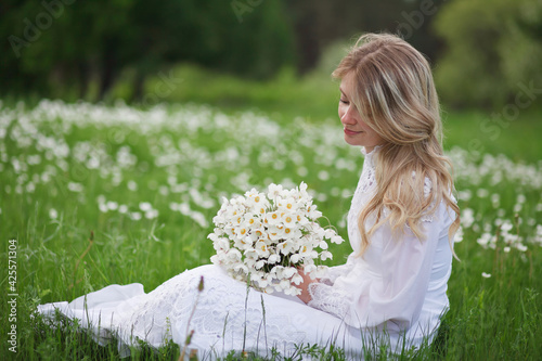 beautiful girl, a blonde in a vintage white dress walks in a blooming apple orchard, a bouquet of anemones, a bride
