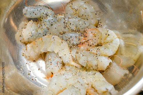 Fresh shrimp marinated with salt and pepper in a silver marinated bowl.