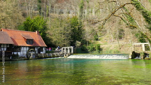 Blautopf mit alter Hammerschmiede in Blaubeuren und blauer Quelle und Stauwehr umgeben von Wald photo