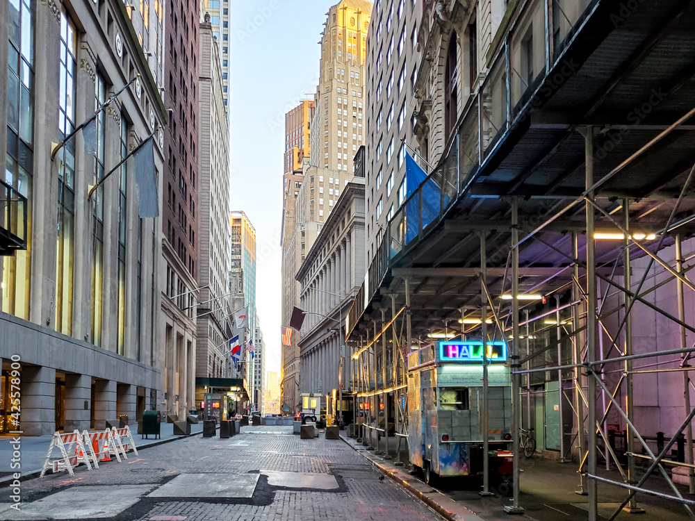 Empty view of the historic buildings along Wall Street with no people and a lonely food cart in the financial district of Manhattan, New York City