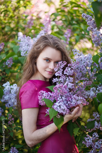 beautiful girl in a short purple dress walks in the lilac garden  leather dress  lilac bloom
