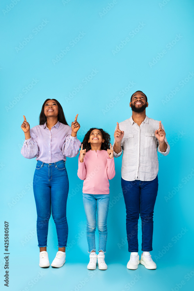 Fototapeta premium Smiling black family pointing up at free copy space