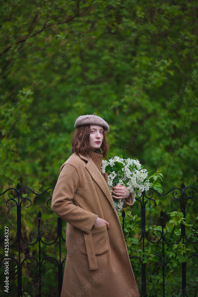 beautiful red-haired girl walks in the garden with a bouquet of bird cherry, red-haired model, rainy weather, image of a Parisian woman beautiful red-haired girl walks in the garden with a bouquet of bird cherry, red-haired model, rainy weather, image of a Parisian woman