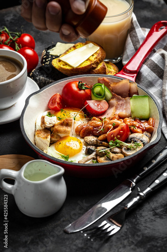 Traditional full English breakfast with fried eggs, beans, mushrooms, grilled and bacon vertical image Food recipe background. Close up