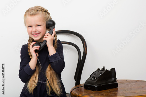 Blonde girl talking by old black phone