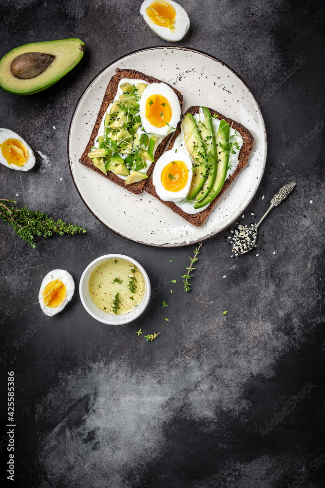 Avocado Sandwiches with Boiled Egg and soft cheese on Cereal Bread. vertical image Food recipe background. Close up