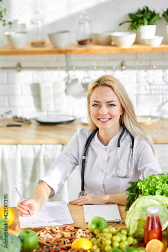 Portrait of young caucasian woman nutritionist in medical gown with fresh vegetables photo