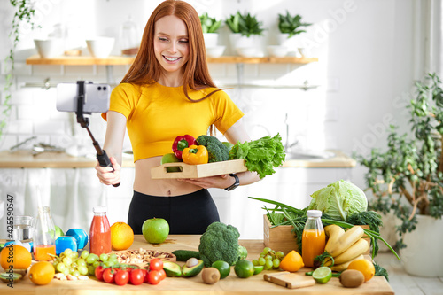 Redhead female preparing healthy lunch for family in modern kitchen, taking vegetables