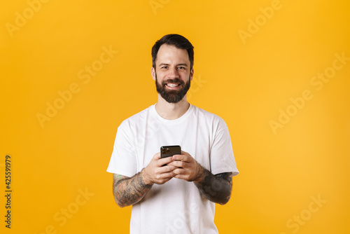Happy mid aged brunette bearded man holding mobile phone