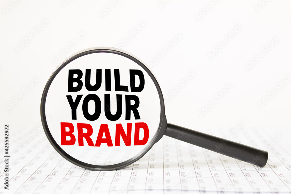 words BUILD YOUR BRAND in a magnifying glass on a white background. business concept words BUILD YOUR BRAND in a magnifying glass on a white background. business concept
