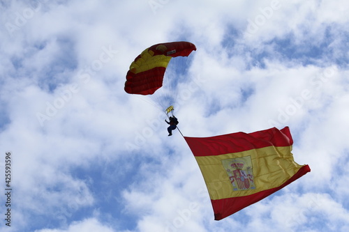 An army paratrooper waving a huge Spanish flag