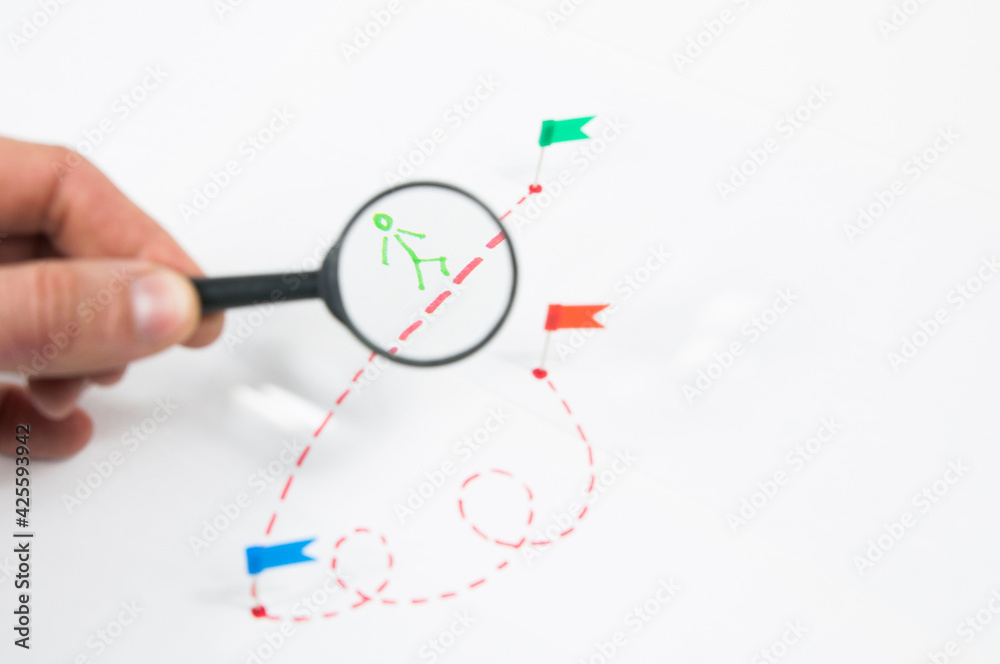 under a magnifying glass, consider a route with a painted little man with flags on a white background under a magnifying glass, consider a route with a painted little man with flags on a white background
