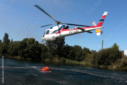 Helicopter collecting water in the river to put out a fire