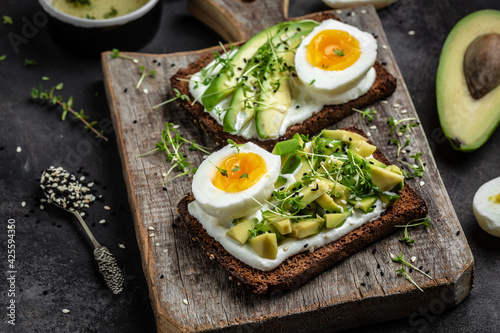 Toast with avocado and egg and soft cheese on Cereal Bread. Food recipe background. Close up. rustic wooden background