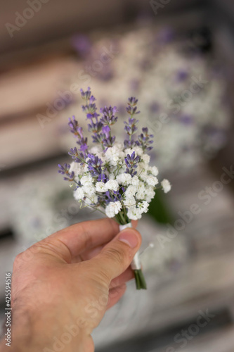 Close up gypsophila and lavender corsage in florist hand