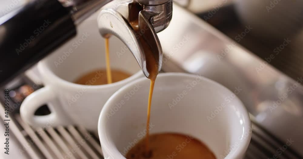 Pouring coffee into two cups, professional espresso machine, extreme closeup