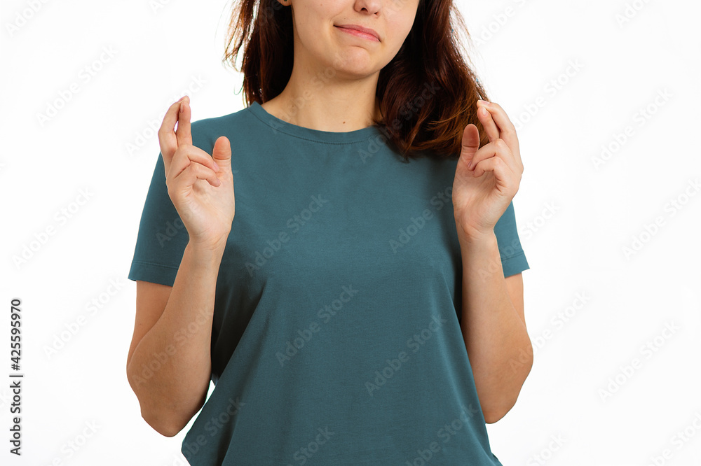 A young woman smiles, fingers crossed. Close-up. White background. Gesture and signs concept A young woman smiles, fingers crossed. Close-up. White background. Gesture and signs concept