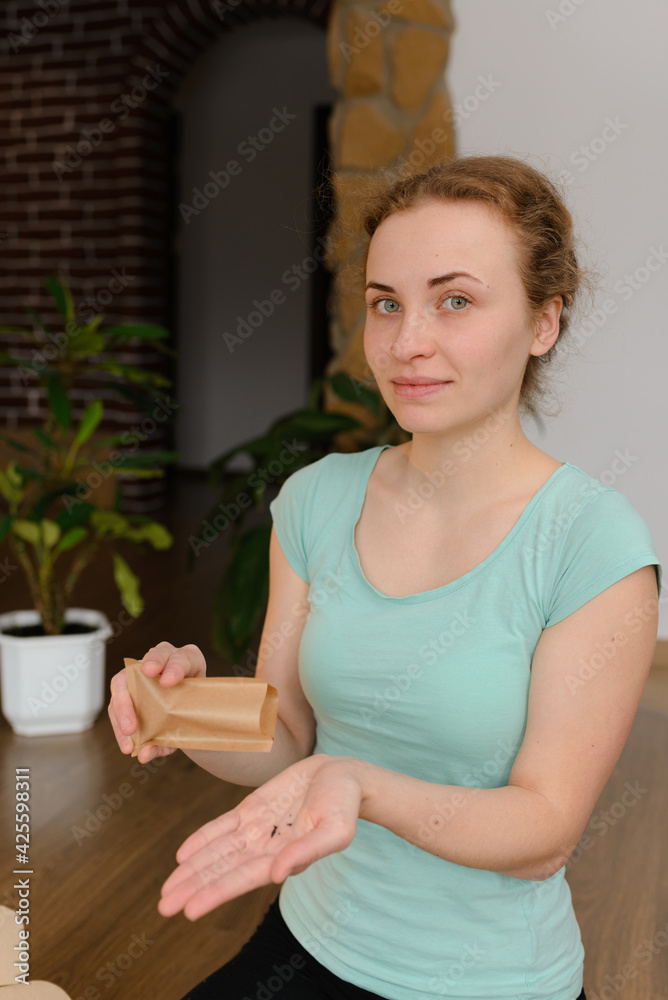 Young woman pours arugula seeds for planting in a microgreen soil substrate