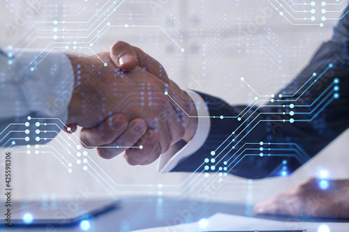Handshake of two businessmen who enters into the contract to develop a new software to improve business service at a company. Technological icons over the table with the document. photo