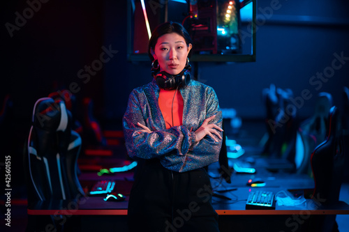 Young asian gamer in a headset poses for the camera with her arms folded