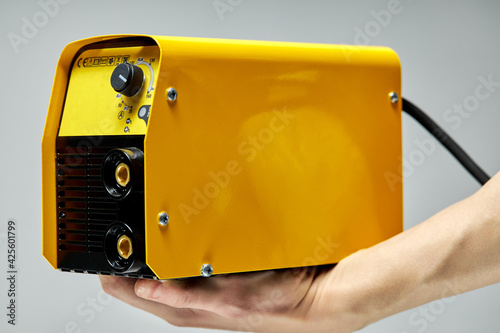 welding inverter machine, yellow colors,in hands of cropped male photo