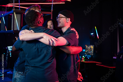 Multi-racial team of esports players tune in to the game and embrace for team spirit boost