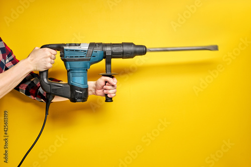 Photos cropped male holding green puncher for repair isolated on yellow