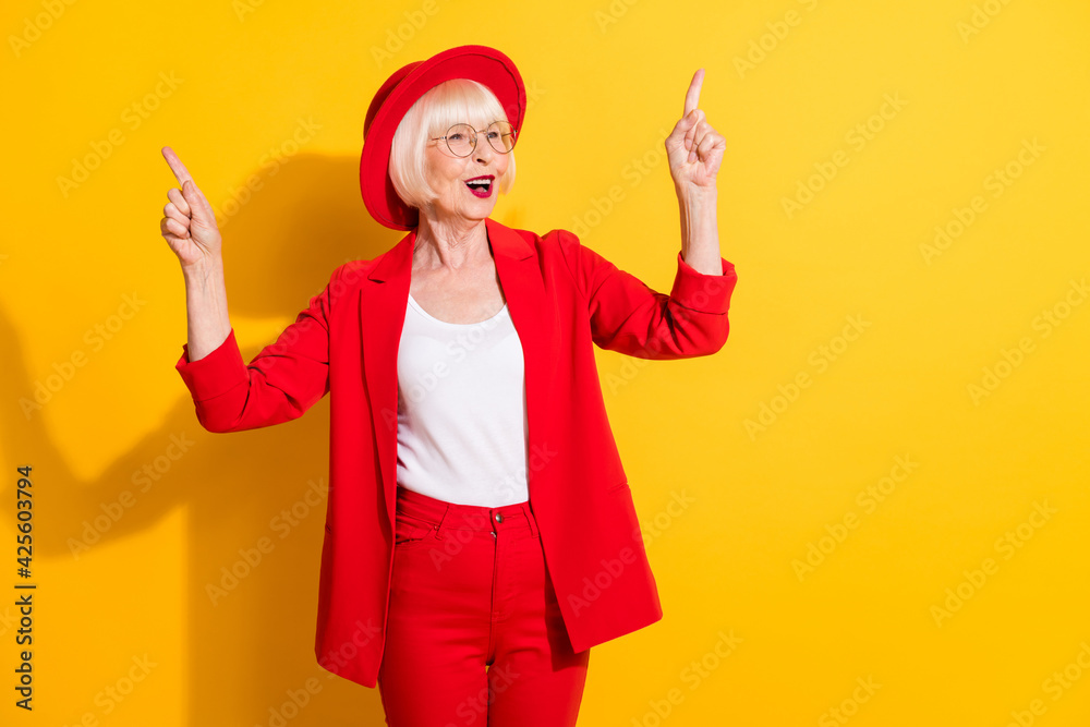 Photo portrait of senior woman wearing red suit headwear enjoying music singing dancing isolated vivid yellow color background Photo portrait of senior woman wearing red suit headwear enjoying music singing dancing isolated vivid yellow color background