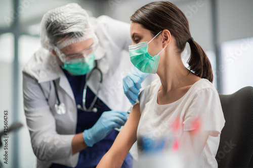 A young woman in a mask decided to get vaccinated against the coronavirus during the pandemic by an experienced doctor in the laboratory