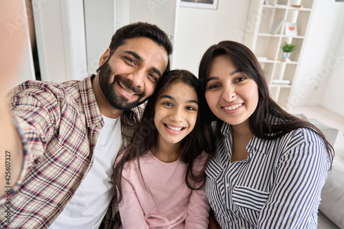 Canvas Print Happy indian couple and teen daughter taking selfie looking at phone camera