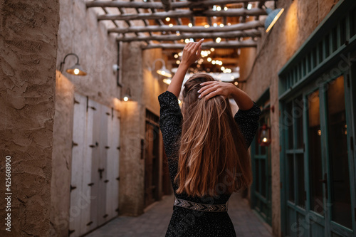 Happy woman traveler wearing black dress walking through the streets