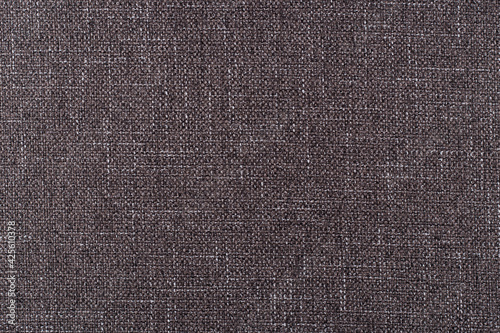 smooth surface of dense upholstery fabric of dark brown color with linen texture, background