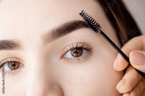 Valokuva Master tweezers depilation of eyebrow hair in women, brow correction with comb