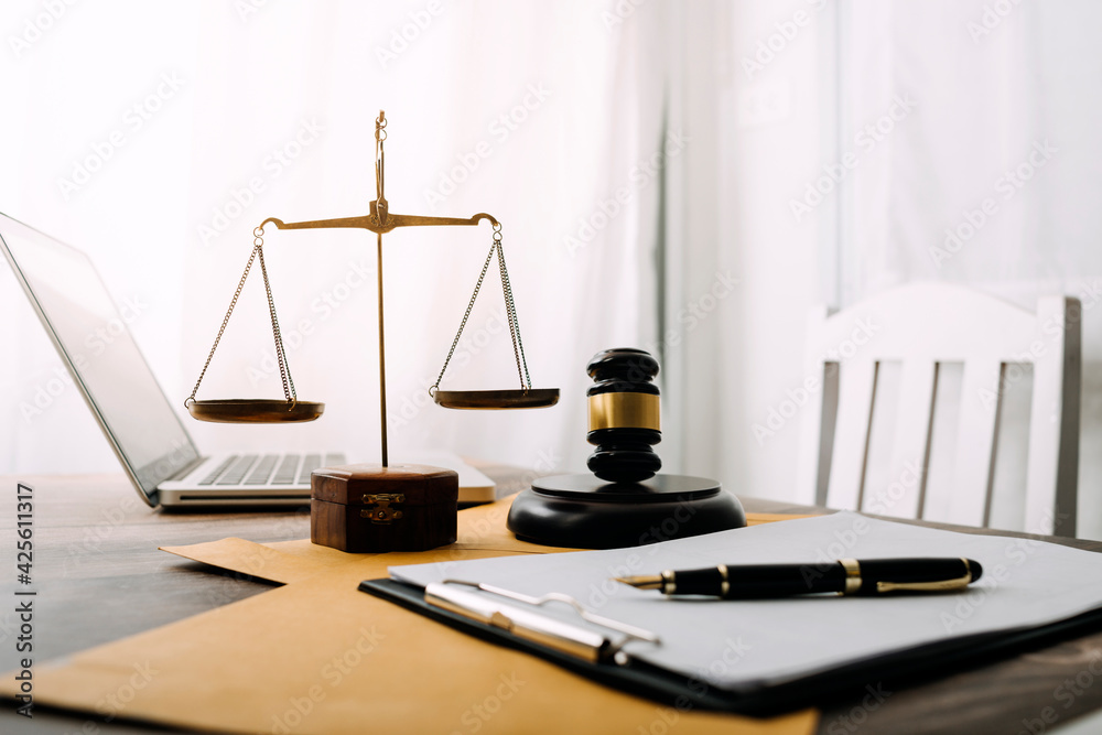 Business and lawyers discussing contract papers with brass scale on desk in office. Law, legal services, advice, justice and law concept picture with film grain effect Business and lawyers discussing contract papers with brass scale on desk in office. Law, legal services, advice, justice and law concept picture with film grain effect