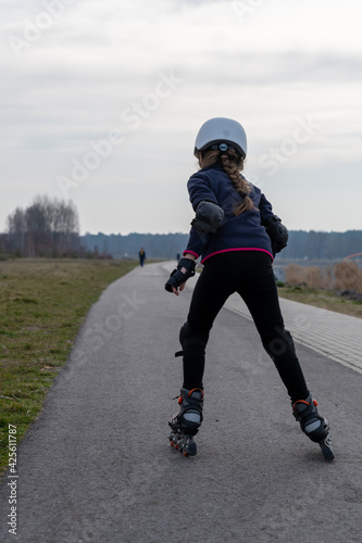 inline skates draußen, ein Mädchen im weißen Helm Rückenansicht. Sport draußen.
