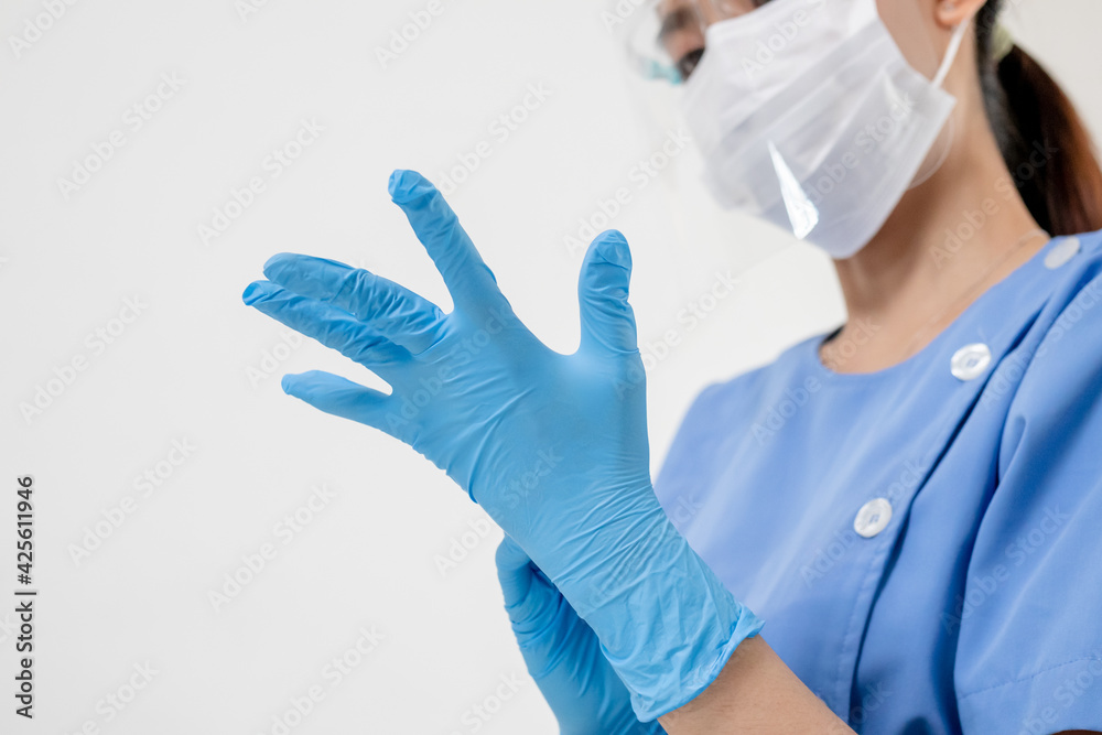 Covid-19,coronavirus hand of young woman doctor or nurse putting on blue nitrile surgical gloves, professional medical safety. Vaccination, immunization or disease prevention against flu concept. - obrazy, fototapety, plakaty 