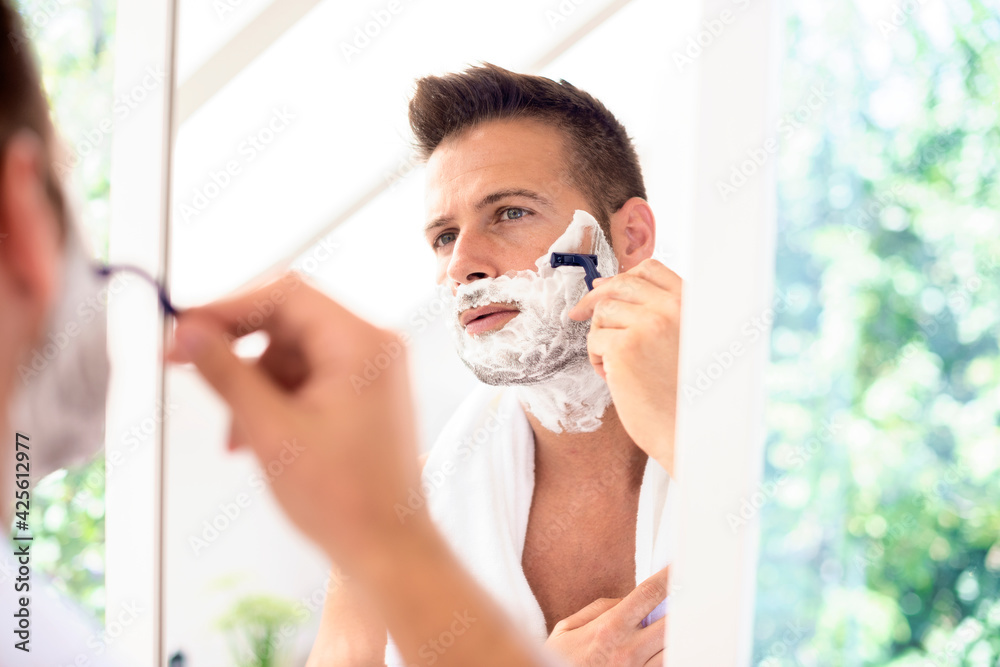 Handsome man shaving his face in the bathroom