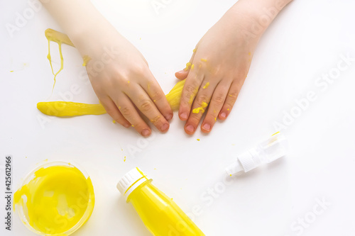 Kid plays with homemade yellow slime. Child hands stretch slime toy. Make slime at home. DIY and children's creativity. Selective focus.