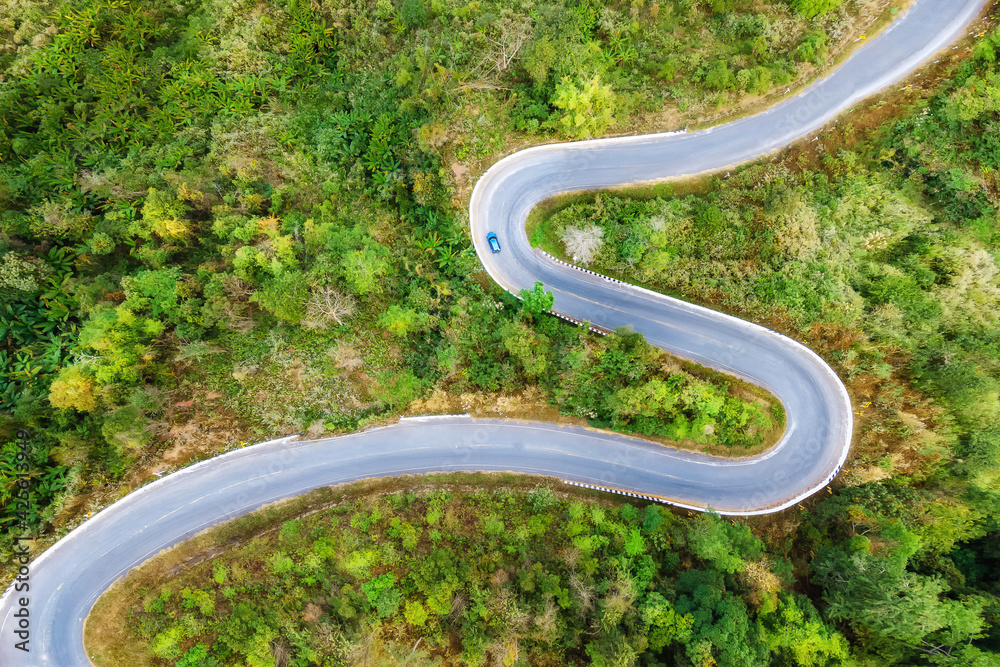 Aerial view of car driving on the road between tropical forest nature landscape
