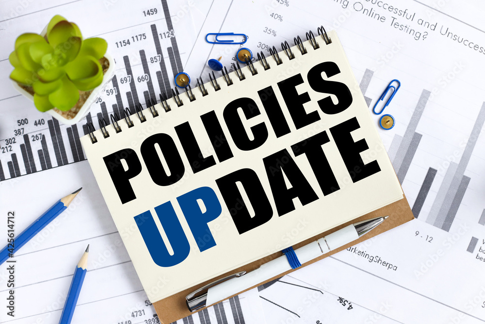 Policies update. text on white notepad paper on a light background near financial charts Policies update. text on white notepad paper on a light background near financial charts
