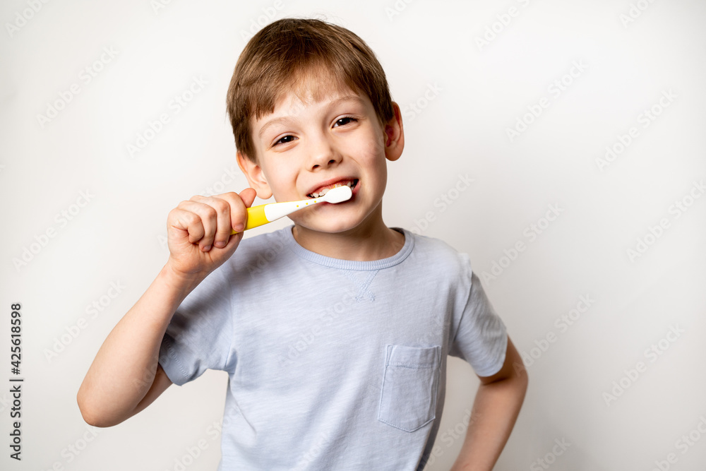 Little boy with a toothbrush on a white background brushes his teeth and smiles close-up, the concept of caring for children's milk teeth Little boy with a toothbrush on a white background brushes his teeth and smiles close-up, the concept of caring for children's milk teeth