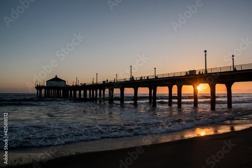 Waves crash against Manhattan Beach pier at sunset