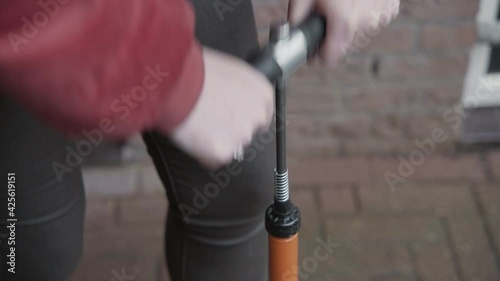 Lady pumps a bicycle tire pump outside to ensure her bike tires have adequate air pressure. photo