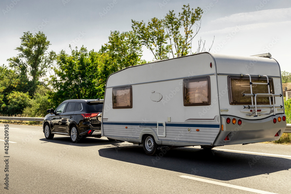 Caravan trailer on a freeway road. Family vacation travel, holiday trip in motorhome RV.