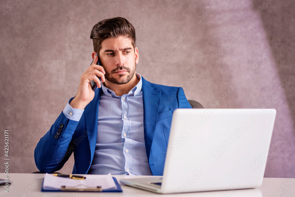 Businessman using mobile phone and laptop while working at the office Businessman using mobile phone and laptop while working at the office